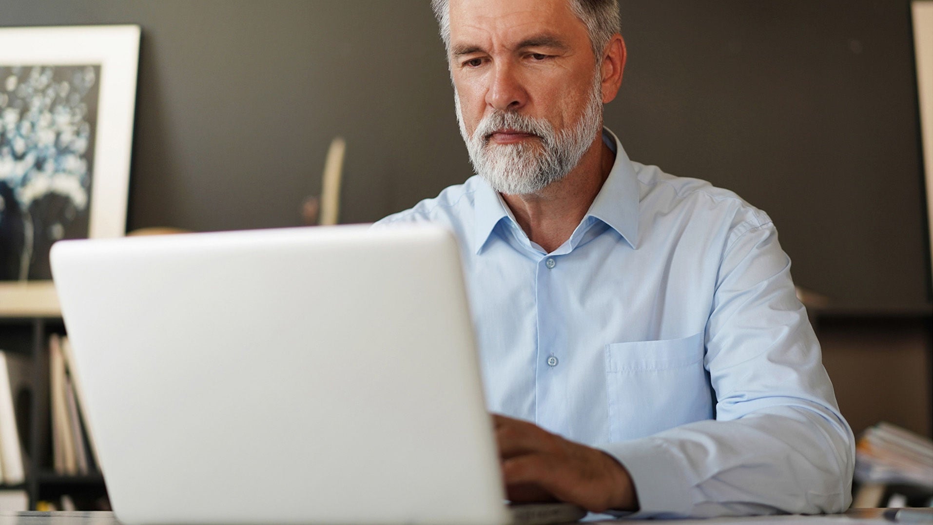 Middle-aged man typing on his laptop.