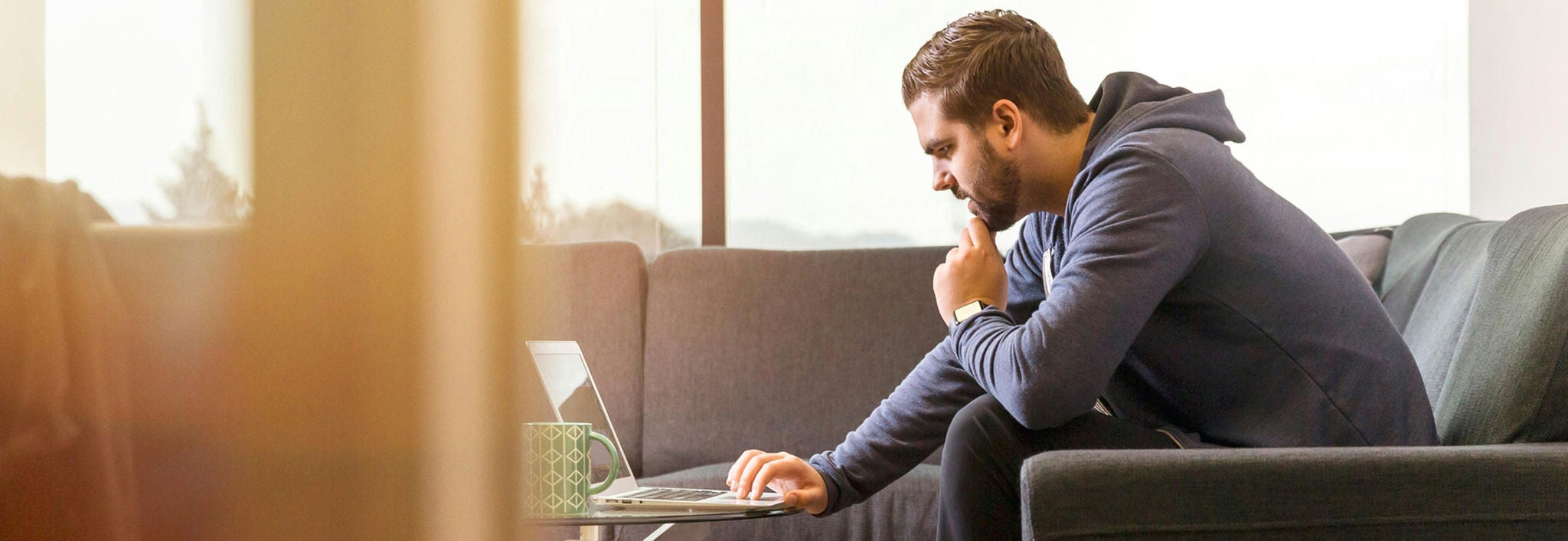 man sitting on couch looking at laptop screen.