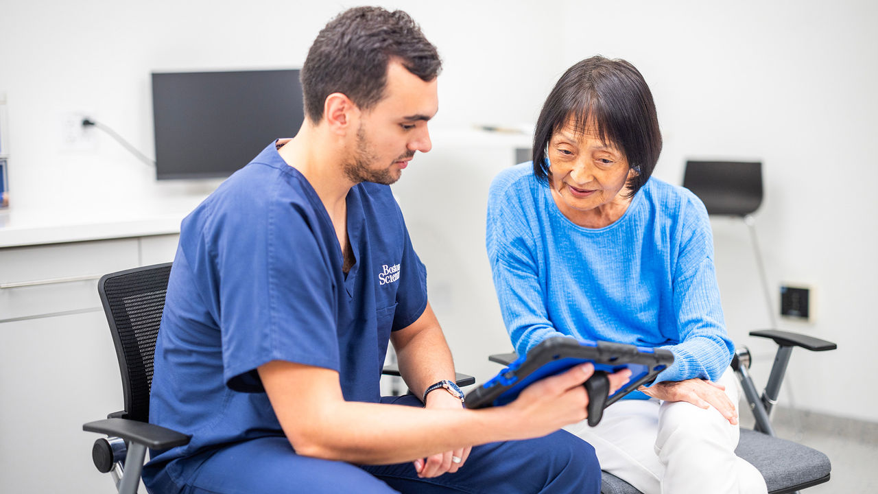 Older woman looking at a tablet held by a healthcare provider.