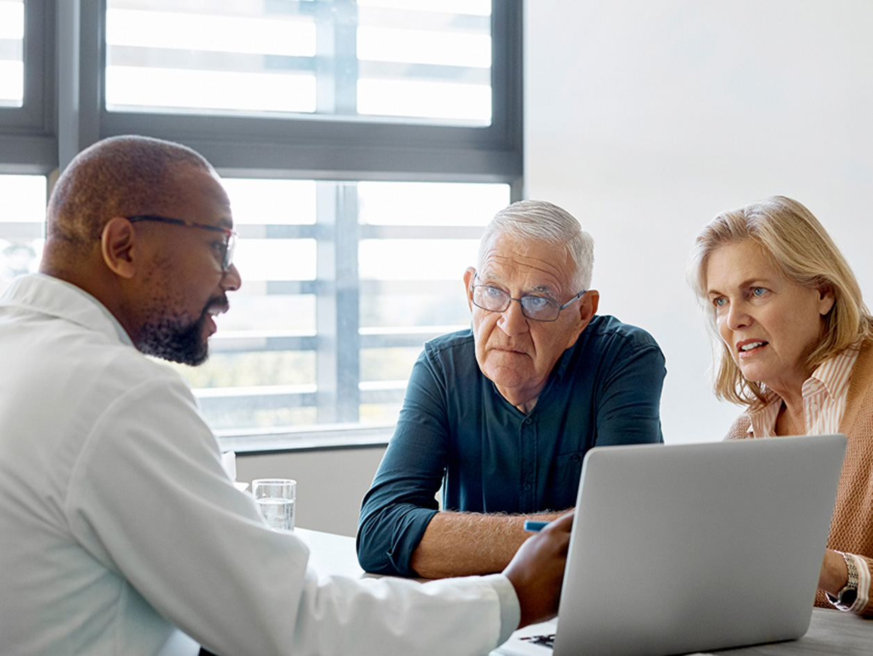 Man and woman sitting at a desk consulting with a physician.