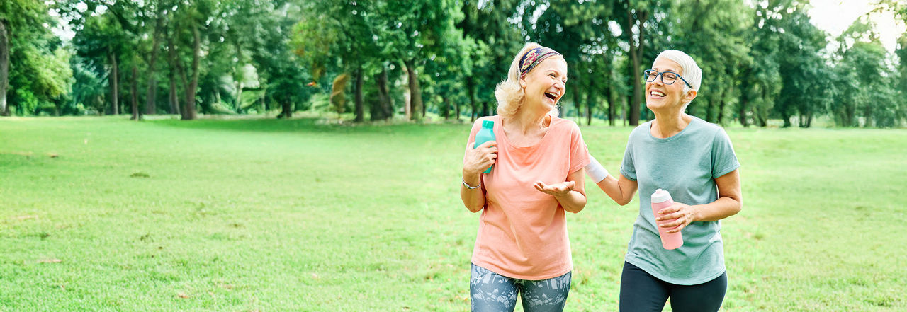 older women walking outside together and laughing.